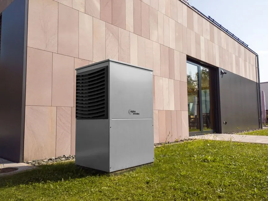 A modern heat pump unit installed outdoors next to a contemporary building, showcasing renewable energy technology.