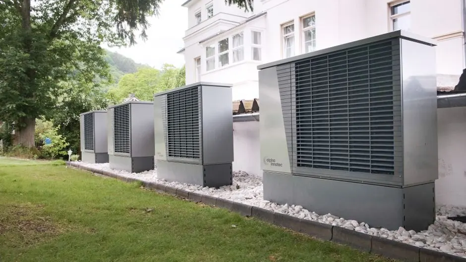 Row of heat pumps outside a building promoting sustainable energy solutions.